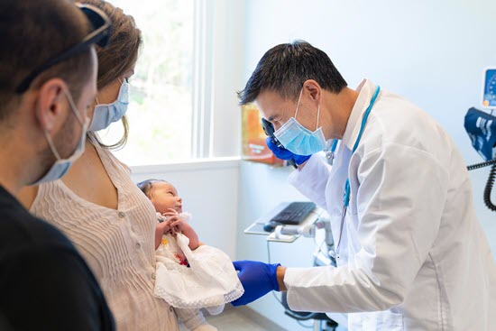 dr. choles examines a small infant being held by her mother